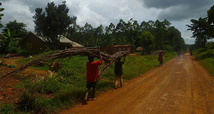 Dirt road with locals carrying bundles of wood